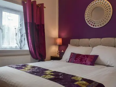 a bedroom with a bed with purple walls and a mirror at The Snug in Aberaeron