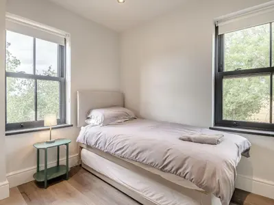 a white bedroom with a bed and two windows at Gwrlodde in Talgarth