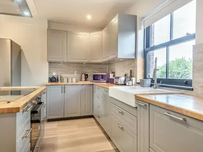 a kitchen with white cabinets and a large window at Gwrlodde in Talgarth