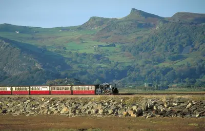 a red and white train on the tracks near mountains at 2 Bed in Dolgellau oc-bow284 in Trawsfynydd