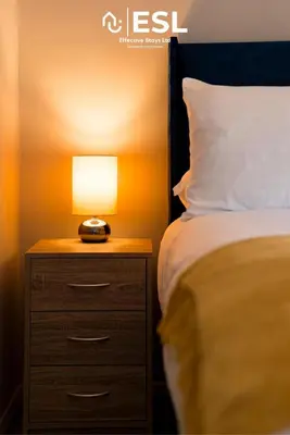 a bed with a night stand with a lamp on it at Comfy Modern 2 Bedroom Duplex Apartment with Sun Terrace in Shrewsbury