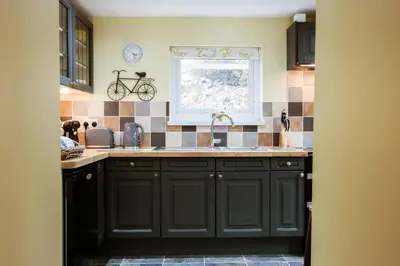 a kitchen with black cabinets and a sink at Cosy, coastal cottage in Snowdonia in Harlech