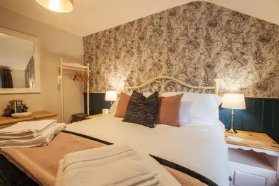 a bedroom with a large white bed with a wallpaper at Cosy, coastal cottage in Snowdonia in Harlech