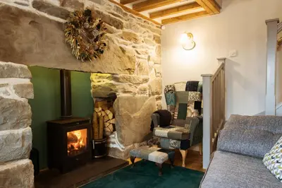 a living room with a stone fireplace and a couch at Cosy, coastal cottage in Snowdonia in Harlech