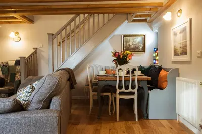 a living room with a table and a staircase at Cosy, coastal cottage in Snowdonia in Harlech