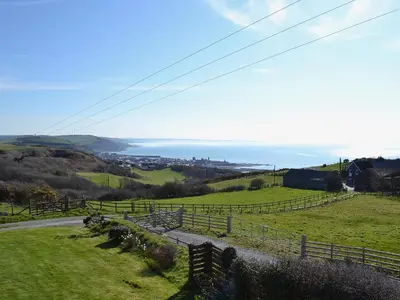 a view of a field with a fence and the ocean at Seascape in Aberystwyth