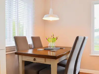 a dining room table with chairs and a vase of flowers on it at Seascape in Aberystwyth