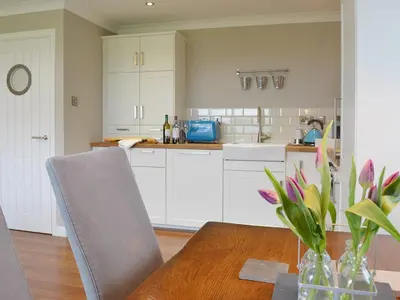 a kitchen with a wooden table and white cabinets at Seascape in Aberystwyth
