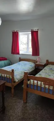 a bedroom with two beds and a window with red curtains at Toad Hall Hostel in Machynlleth