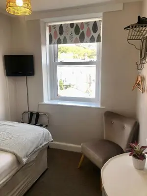 a bedroom with a bed and a window and a chair at Cranwell Court Apartments in Aberystwyth