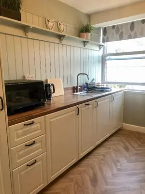 a kitchen with white cabinets and a sink and a microwave at Cranwell Court Apartments in Aberystwyth