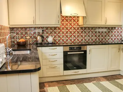 a kitchen with white cabinets and a tile wall at Denbigh Hall in Leominster