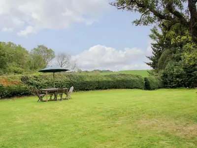 a picnic table with an umbrella in a field at Denbigh Hall in Leominster