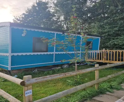 a blue tiny house in a yard next to a fence at Glamping Hut - Riverview 3 in Welshpool