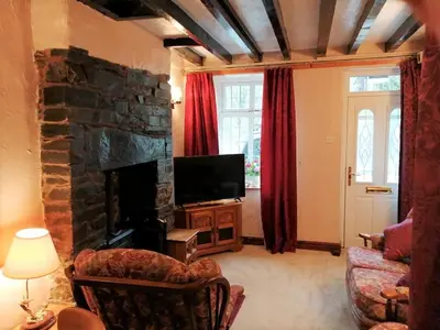 a living room with a stone fireplace and a television at 1 Park Terrace in Corris