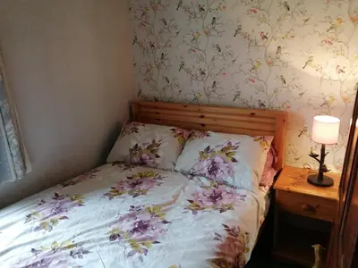 a bedroom with a bed with flowers on the wall at 1 Park Terrace in Corris