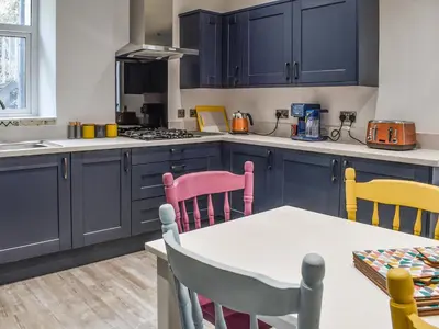 a kitchen with blue cabinets and a table and chairs at Ty Isaf in Barmouth