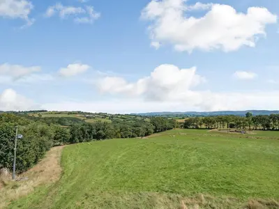 a field of grass with sheep in the distance at Penceunant in Penuwch