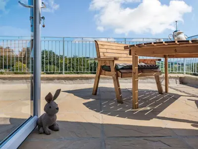 a stuffed rabbit sitting next to a bench on a balcony at Penceunant in Penuwch