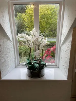 a vase of flowers sitting on a window sill at Penddol Cottage Llangollen in Llangollen