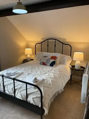 a bedroom with a large white bed with two lamps at Penddol Cottage Llangollen in Llangollen