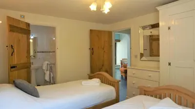 a bedroom with two beds and a bathroom with a shower at Sheep Dip Cottage - 5* Cyfie Farm, with log burner and private hot tub in Llanfyllin