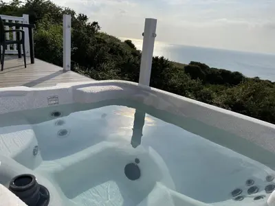 a hot tub on a patio with the ocean in the background at Sea Breeze Lodge in Aberaeron