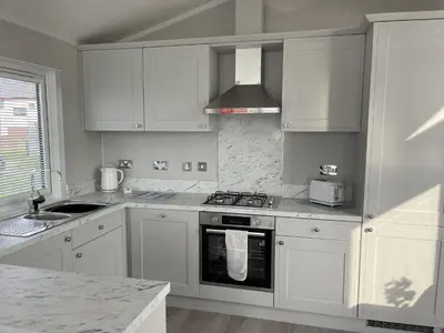 a kitchen with white cabinets and a stove top oven at Sea Breeze Lodge in Aberaeron