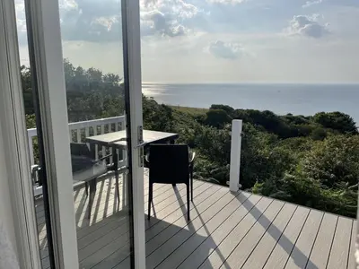 a balcony with a table and a view of the ocean at Sea Breeze Lodge in Aberaeron