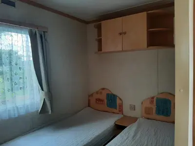 two beds in a small room with a window at Cadwgan Caravan in Dyffryn