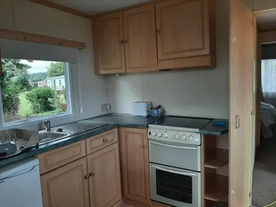 a kitchen with a stove and a sink and a window at Cadwgan Caravan in Dyffryn