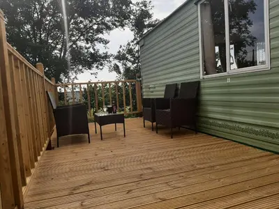 a wooden deck with chairs and a house at Cadwgan Caravan in Dyffryn