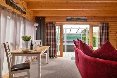 a dining room with a table and a red couch at Finest Retreats - Garden Lodge in Craven Arms