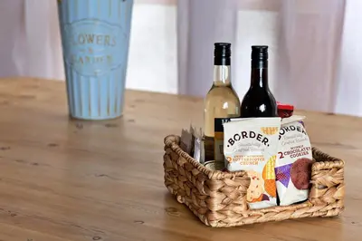a basket of wine and snacks on a table at Finest Retreats - Garden Lodge in Craven Arms