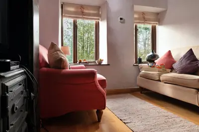 a living room with a red chair and a couch at Finest Retreats - Dolwar Cottage in Ffestiniog