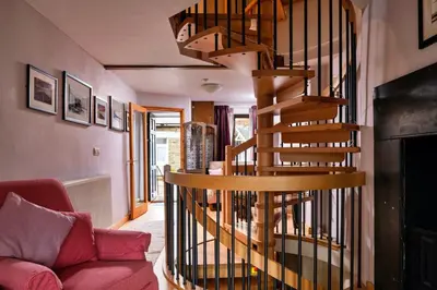 a spiral staircase in a living room with a red couch at Finest Retreats - Dolwar Cottage in Ffestiniog
