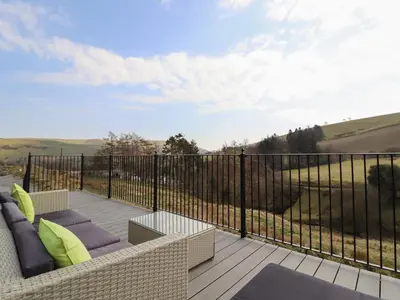 a patio with a couch and chairs on a balcony at The Sheep Shed in Oswestry