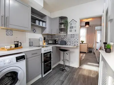 a kitchen with white cabinets and a washer and dryer at Central cosy home 5 minutes walk from Shrewsbury - Pass the Keys in Shrewsbury