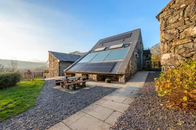 an exterior view of a stone building with a picnic table at 2 Bed in Dolgellau oc-bow282 in Trawsfynydd
