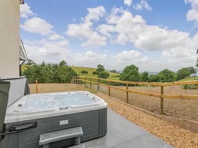 a hot tub sitting on the side of a house at Upper Bryn Y Groes in New Bridge