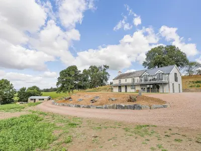 a house on top of a hill with a dirt road at Upper Bryn Y Groes in New Bridge