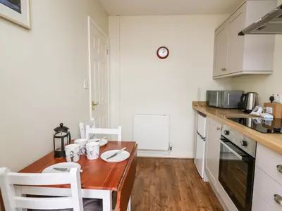 a kitchen with a wooden table and white cabinets at Primrose Cottage in Llandrindod Wells