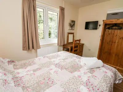 a bedroom with a bed with a quilt on it at Primrose Cottage in Llandrindod Wells