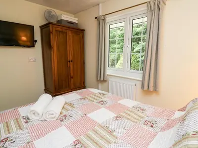 a bedroom with a bed with towels on it at Honeysuckle Cottage in Llandrindod Wells