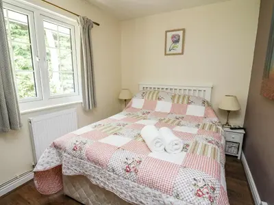 a bedroom with a bed with two towels on it at Honeysuckle Cottage in Llandrindod Wells