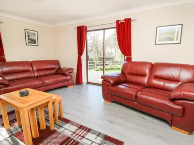 a living room with two leather couches and a table at Glyn Cottage in Llanon