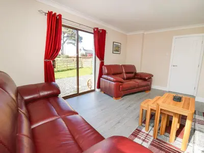 a living room with a leather couch and a table at Glyn Cottage in Llanon