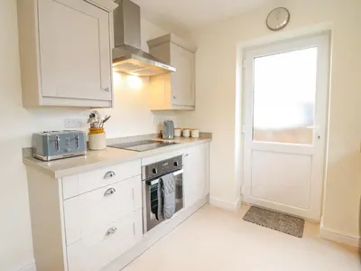 a kitchen with white cabinets and a window at Mawnog Fach in Bala