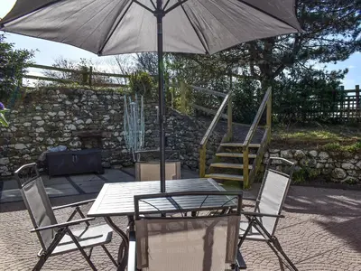 a table with an umbrella and two chairs and a ladder at Morannedd Bach in Dyffryn