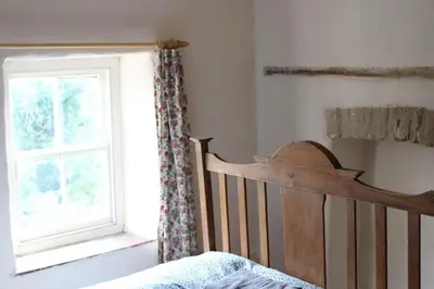 a bedroom with a crib and a window at Rhandirmwyn - Cottage - Sleeps 4 - Pet Friendly in Llandovery